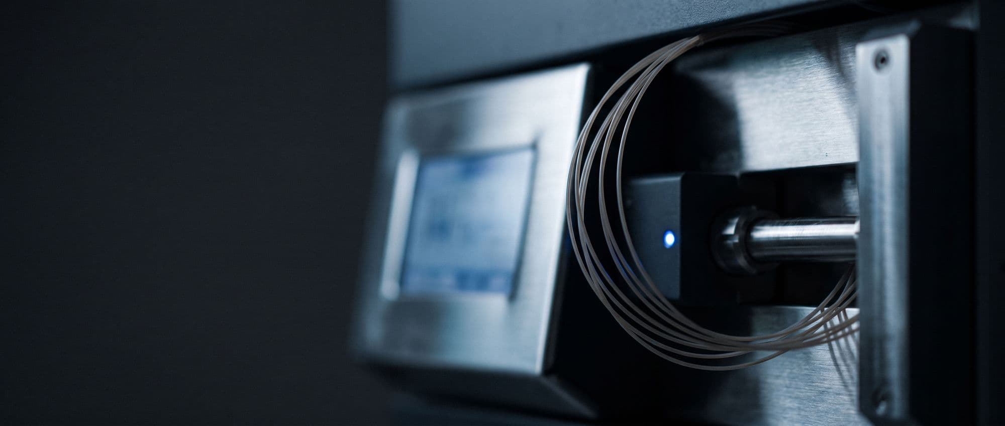 Close detail of a liquid chromatography system, capillary tubing curved against brushed steel